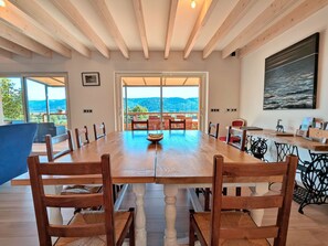 A dining area with a large wooden table, chairs, and a view of the outdoors. - Spacious cottage for 10 in Vagney - Sauna, games, near Gérardmer (Vagney)