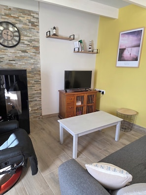 Un salon avec un téléviseur, un meuble en bois et un canapé.