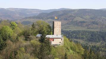 Une petite tour de pierre, surmontée d’un drapeau, entourée d’arbres et de collines.