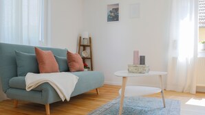 Uma sala de estar moderna com um sofá azul-turquesa, uma mesa de centro branca e um tapete estampado.