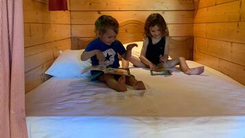 Una habitación de cabaña de madera con dos niños leyendo en una cama.