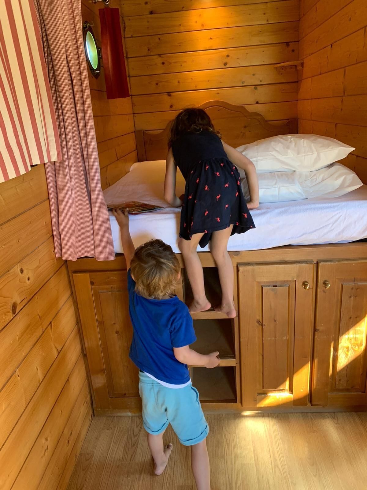 Interno di una baita in legno con un letto, un piccolo armadio e una finestra.