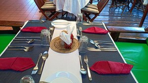 A dining table set with a white tablecloth, red napkins, and silverware. - Mathioya River Lodge (Gacharageini)