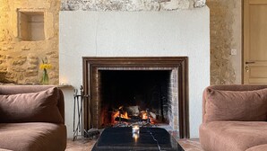 Una habitación acogedora con chimenea de piedra, dos sofás y una mesa de centro con velas.