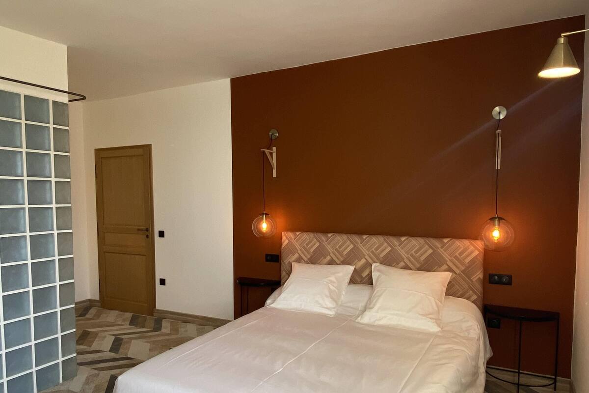 A hotel room with a large bed, two bedside lamps, a patterned carpet, and a door.