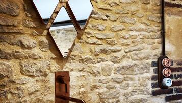 A stone wall with a rustic sink and a mirror.