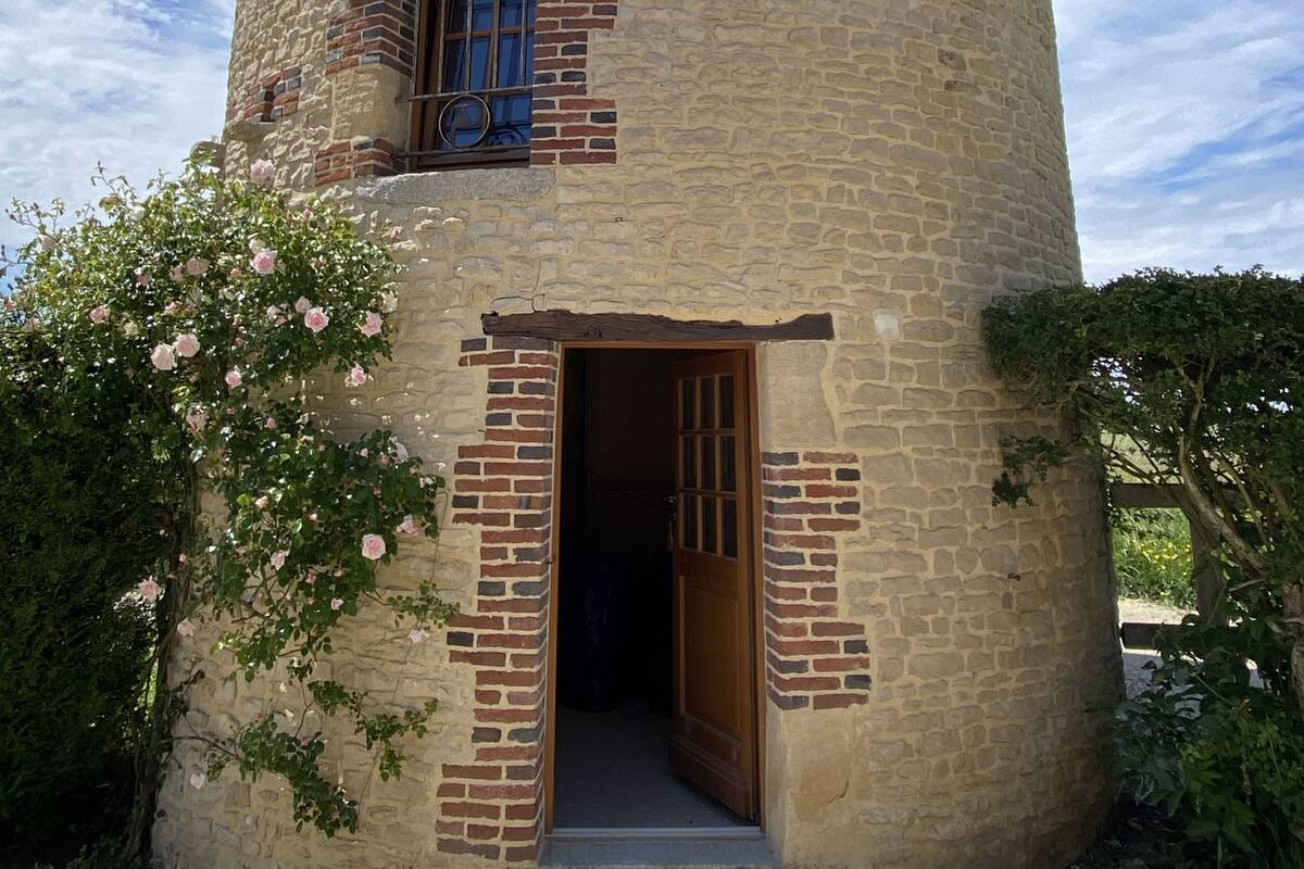 A stone tower with a wooden door and a small window, surrounded by greenery.