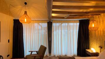 A cozy bedroom with a wooden ceiling, a bed, a chair, and two hanging lamps.