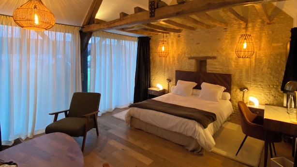 Un dormitorio acogedor con techo de madera, cama, escritorio y una silla.