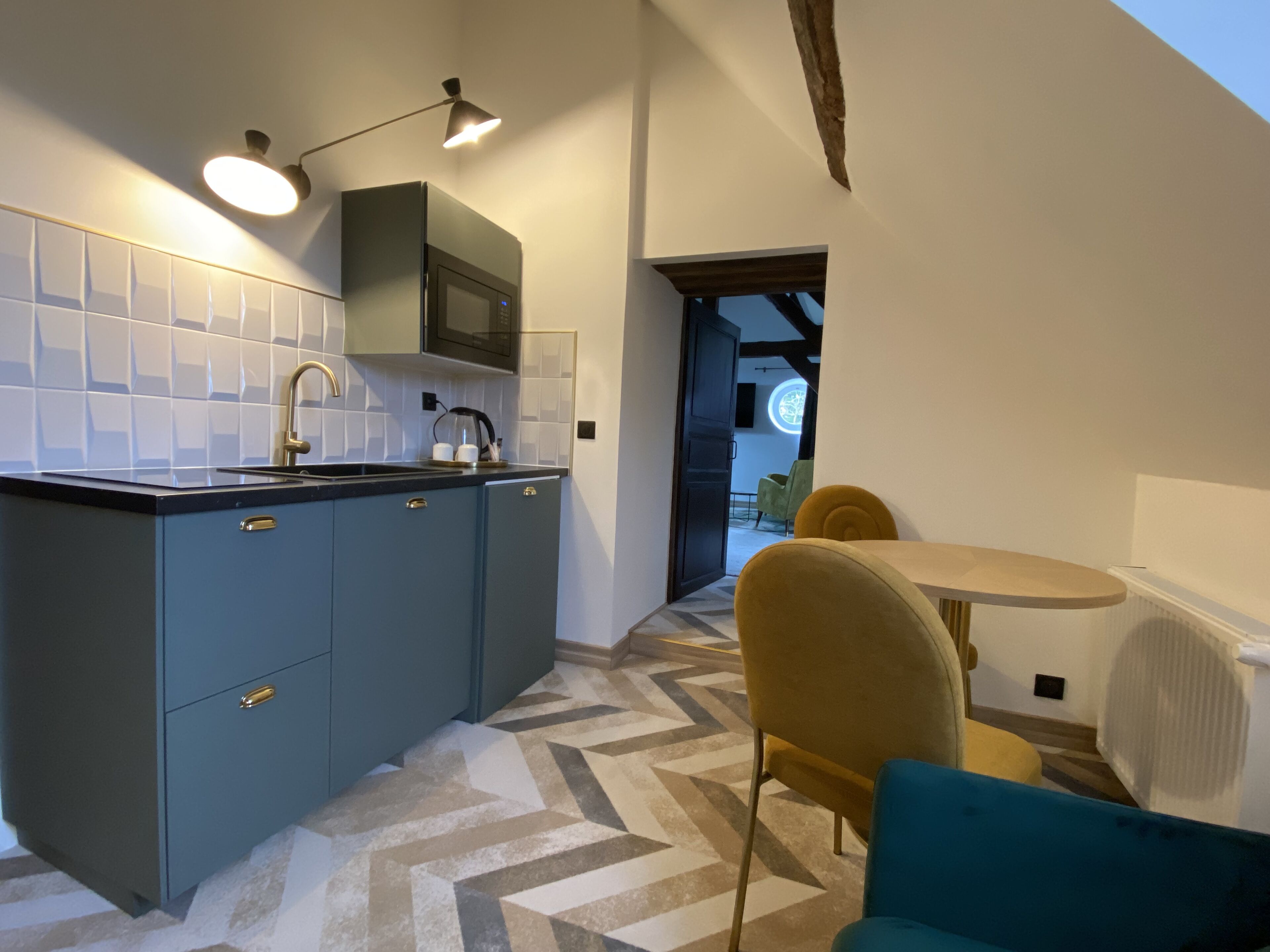Eine moderne Küche mit integriertem Mikrowellenherd, Spüle und Kaffeemaschine. Ein Essbereich mit Tisch und Stühlen lädt zum Verweilen ein, und ein großes Fenster sorgt für natürliches Licht.