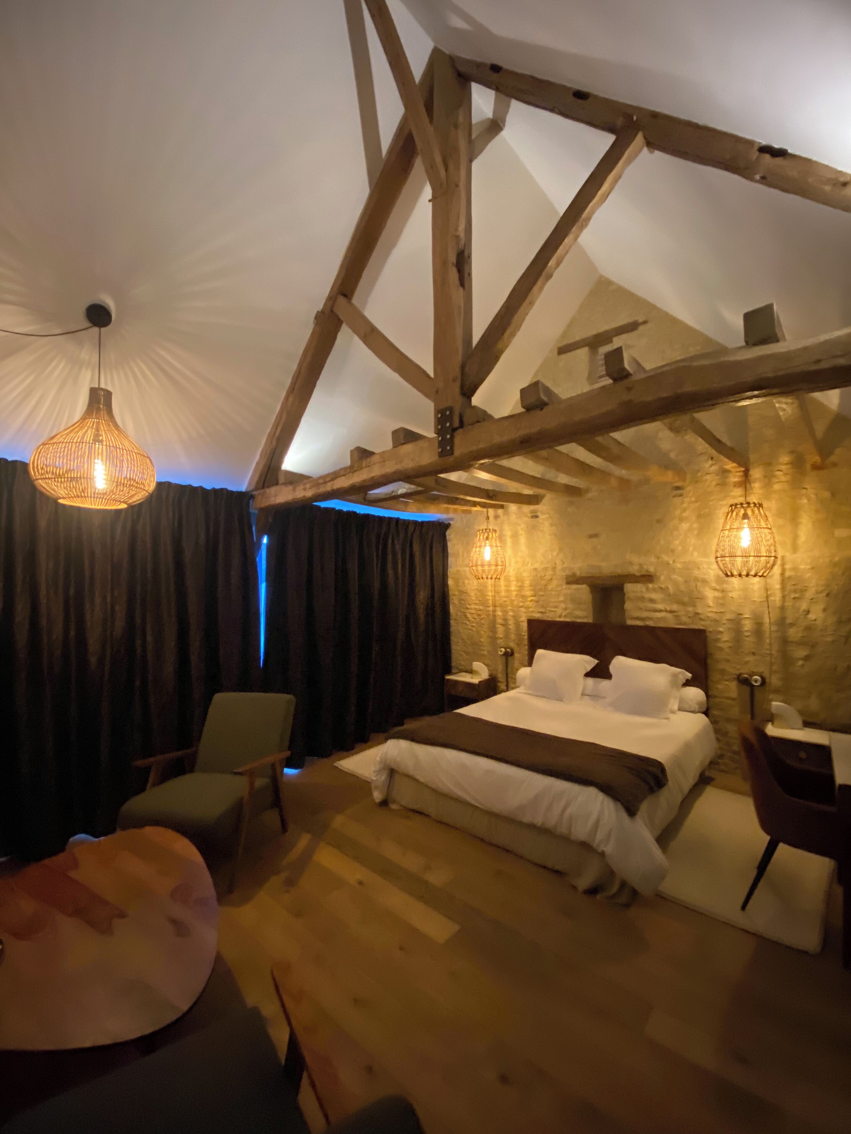 Una camera da letto accogliente con soffitto in legno, un letto grande, un comodino e un lampadario.