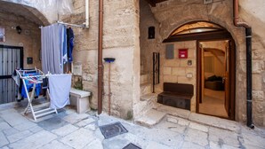 Edificio de piedra con zona de lavandería, puerta de madera y un cartel con el número 48.