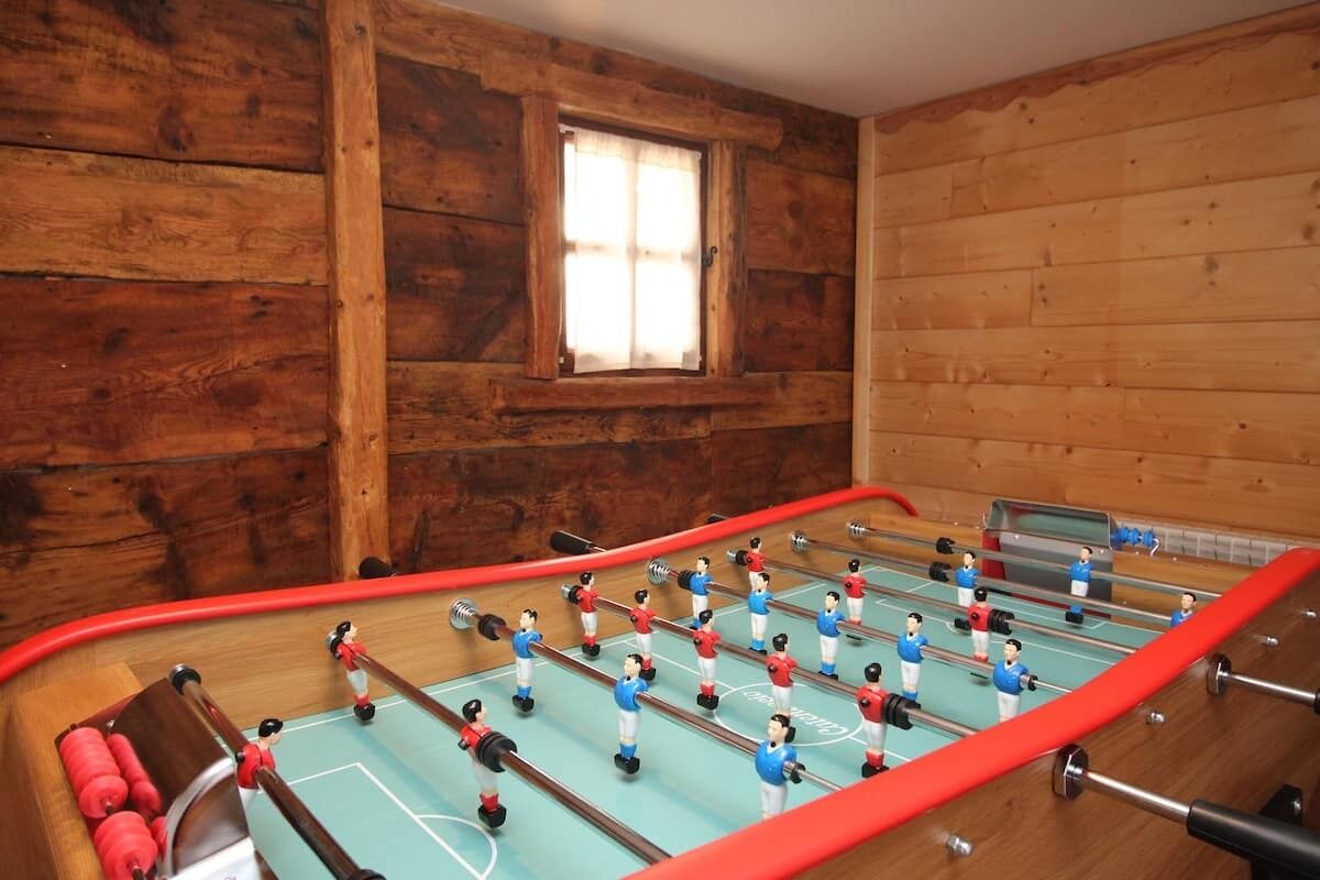 A foosball table in a room with wooden walls and a window.