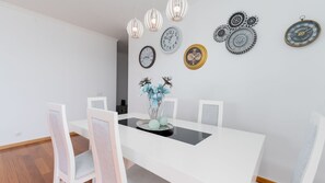 Un coin repas avec une table blanche, des chaises et un vase rempli de fleurs.