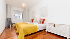 Habitació d'hotel amb dos llits, una cadira, un taulell blanc i decoració mural.
