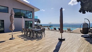 Un patio moderno al aire libre con piscina, sillas de descanso y sombrillas.