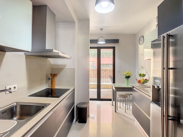 Een moderne keuken met roestvrijstalen apparatuur, een centraal kookeiland en uitzicht naar buiten.