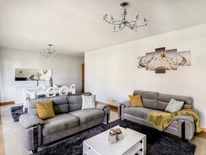 Una sala de estar moderna con dos sofás grises, una mesa de centro blanca y una araña.