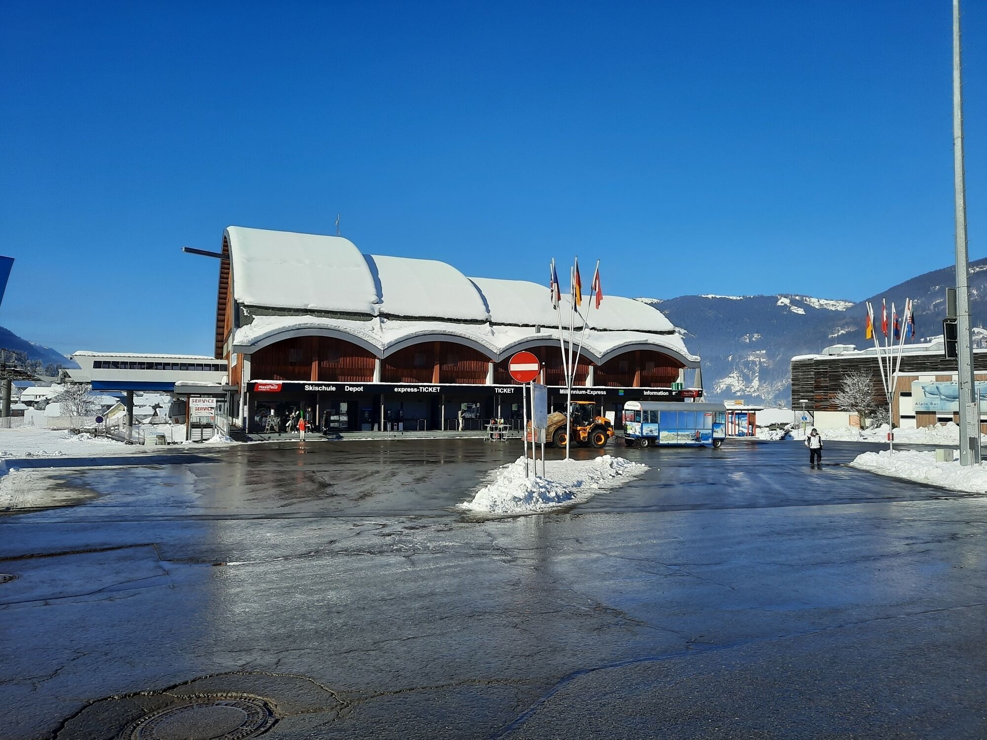 A building with a snow-covered roof and multiple entrances, including a ticket booth and a service area.