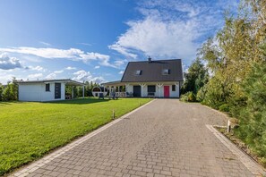 A house with a paved driveway leading to a front door, a small shed, and a well-maintained lawn.