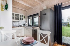 A kitchen with white cabinets, a stainless steel refrigerator, and a window with a view of the outdoors.