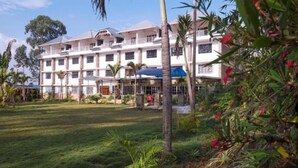 Een meerlaags hotel met een centrale binnenplaats, omringd door weelderige begroeiing en palmbomen.