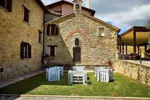 A stone building with a small courtyard, white outdoor furniture, and a stone wall. - Inviting 15 Guests Villa (Monte Santa Maria Tiberina)