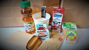 Variedad de alimentos, incluyendo una botella de Paquito, un tarro de Nutella, una caja de leche, una caja de chocolate con leche y pan.