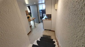 A narrow staircase leading to a kitchen area with a microwave on a counter. - NancyRoom (Vandœuvre-lès-Nancy)