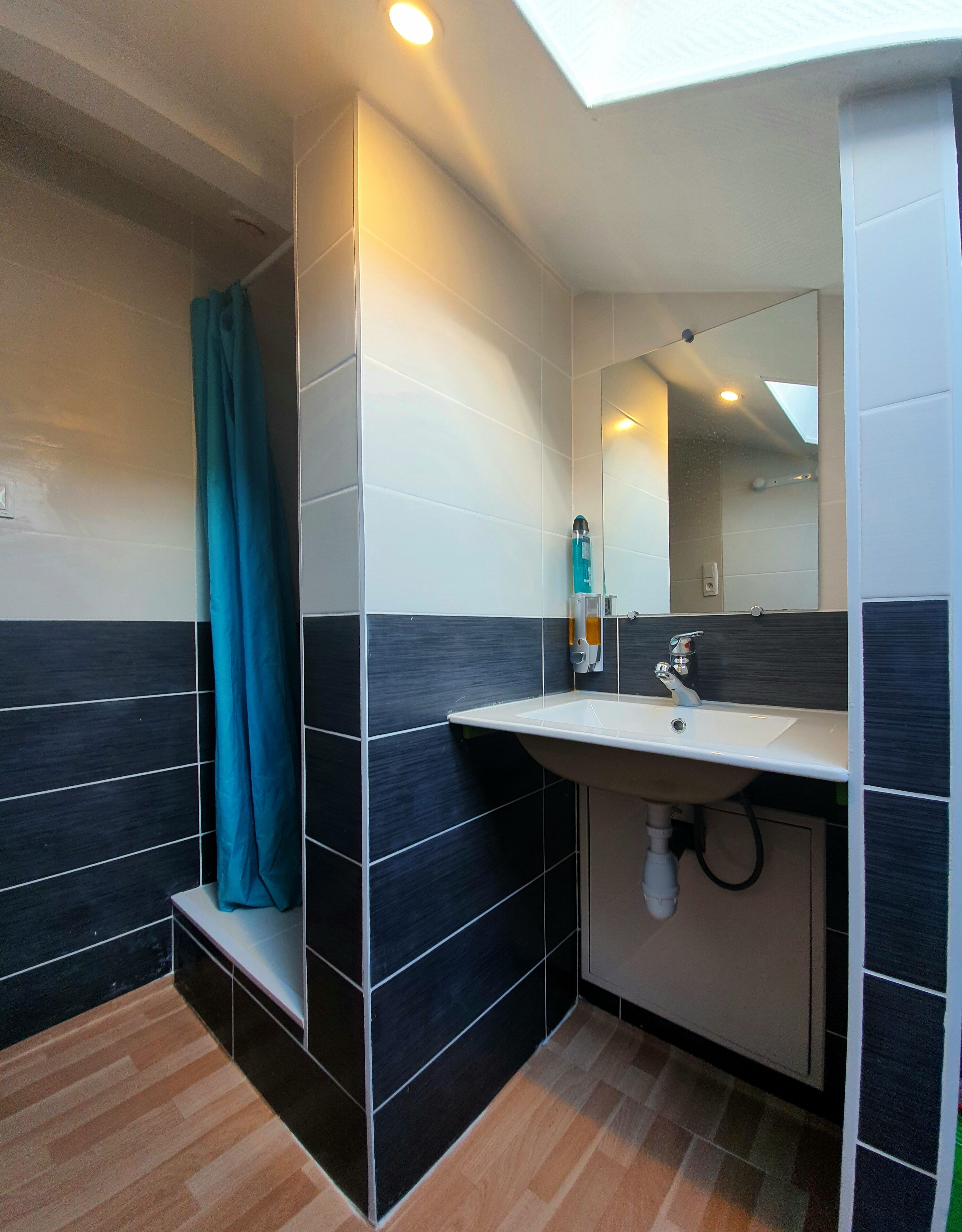 Une salle de bain moderne avec un lavabo, un miroir et un espace douche.