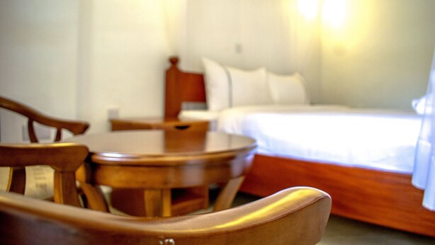 Una habitación de hotel con estructura de cama de madera, una mesa redonda de madera y una silla.