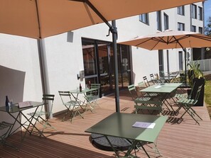 An outdoor patio area with tables and chairs, some under umbrellas, and a building in the background. - Campanile Saint-Brieuc Centre - Gare (Saint-Brieuc)