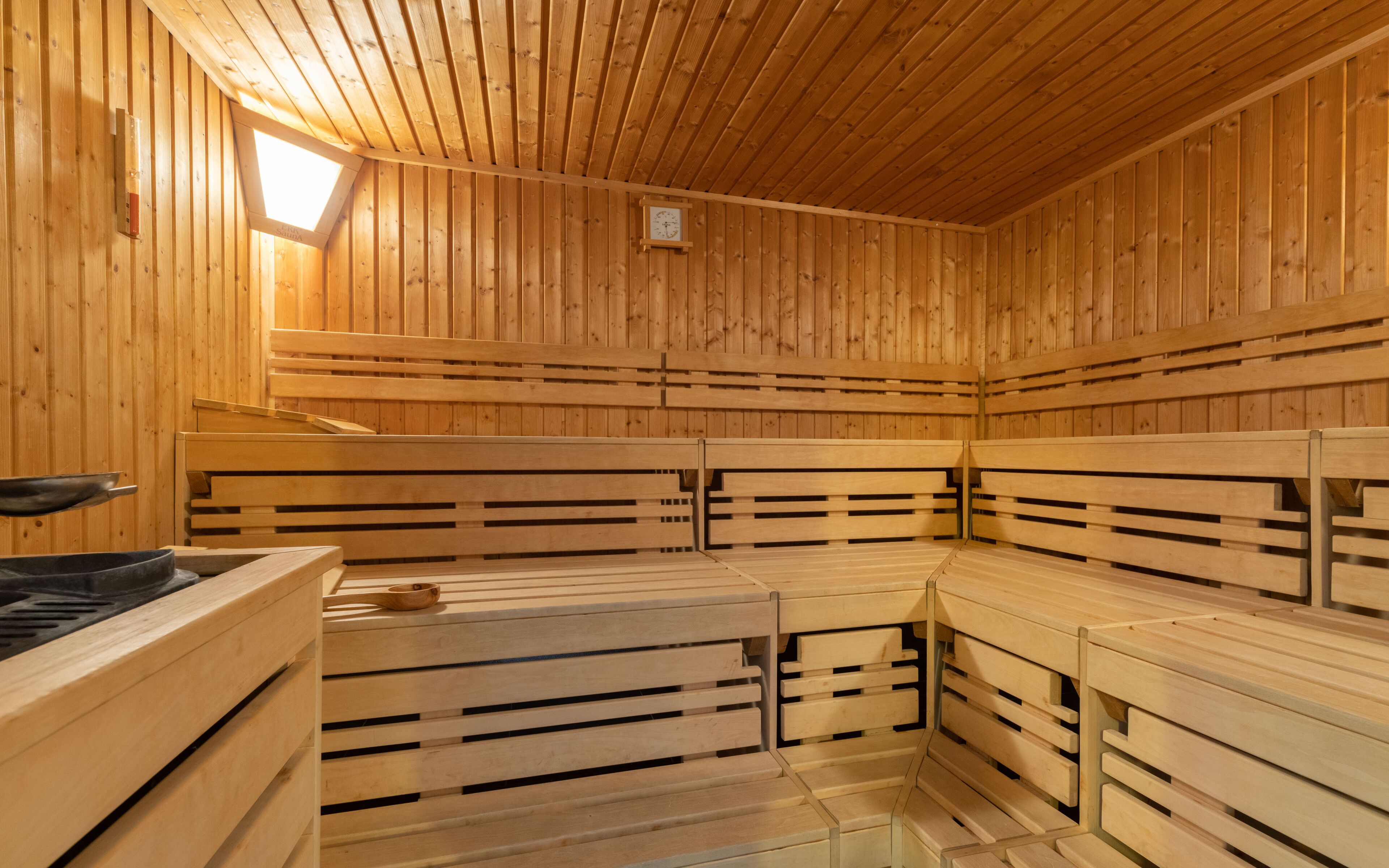 Una sauna con bancos de madera y un reloj visible en la pared.