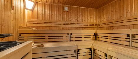 Una sauna con bancos de madera y un reloj visible en la pared.