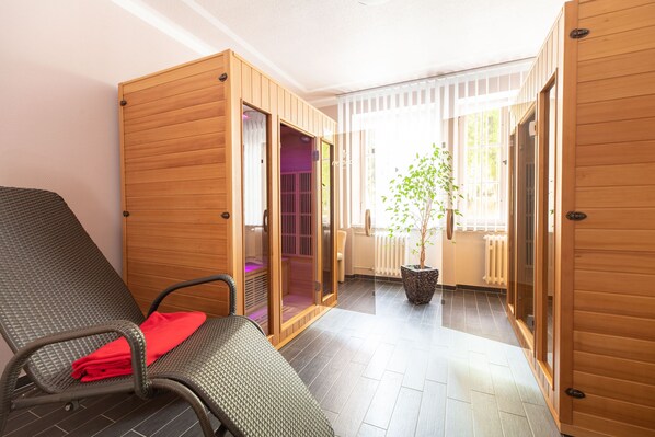 Habitación con sillón de masajes, puertas correderas de madera, una planta en maceta y vista al exterior.