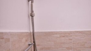 Une douche équipée d’un pommeau de douche à main et d’un robinet mural.
