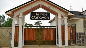 Ingang van een caravanpark met een bord waarop staat 'The Place Caravan' en een hekwerk.