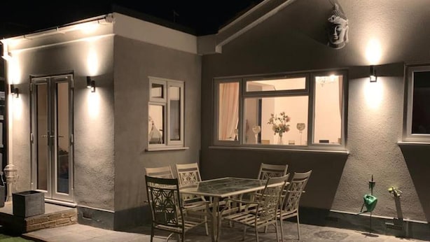Una casa con patio, una mesa de comedor con sillas y una estatua.