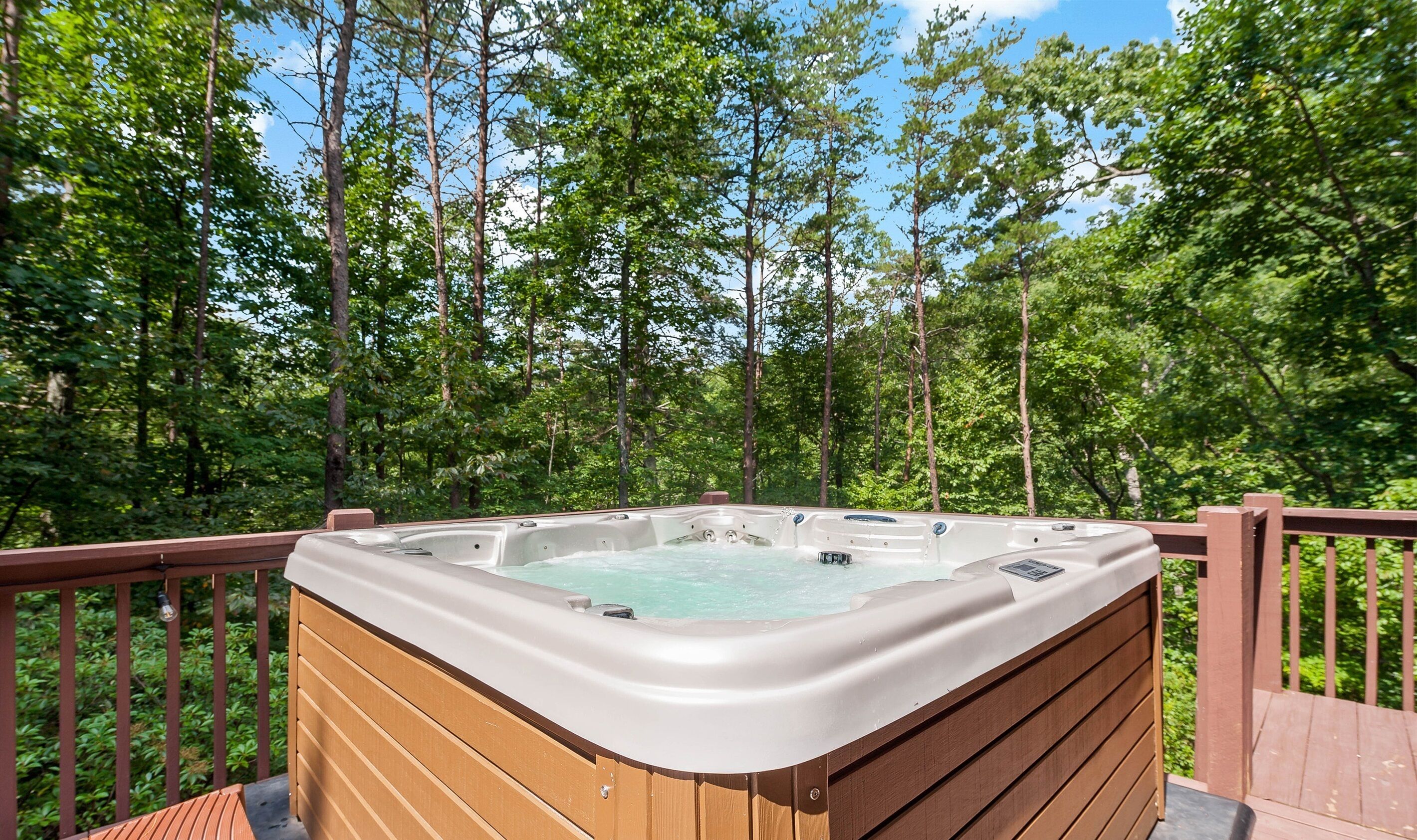 Un jacuzzi en una terraza de madera rodeado de bosque.