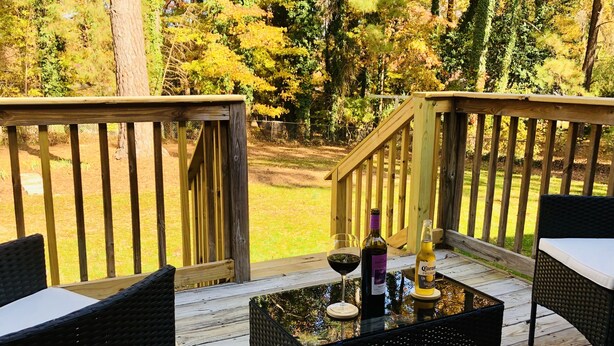 A wooden deck with outdoor furniture, a glass table, and two bottles of wine.