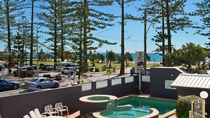 Ein Poolbereich mit Liegestühlen, einem Whirlpool und Blick auf Strand und Meer.
