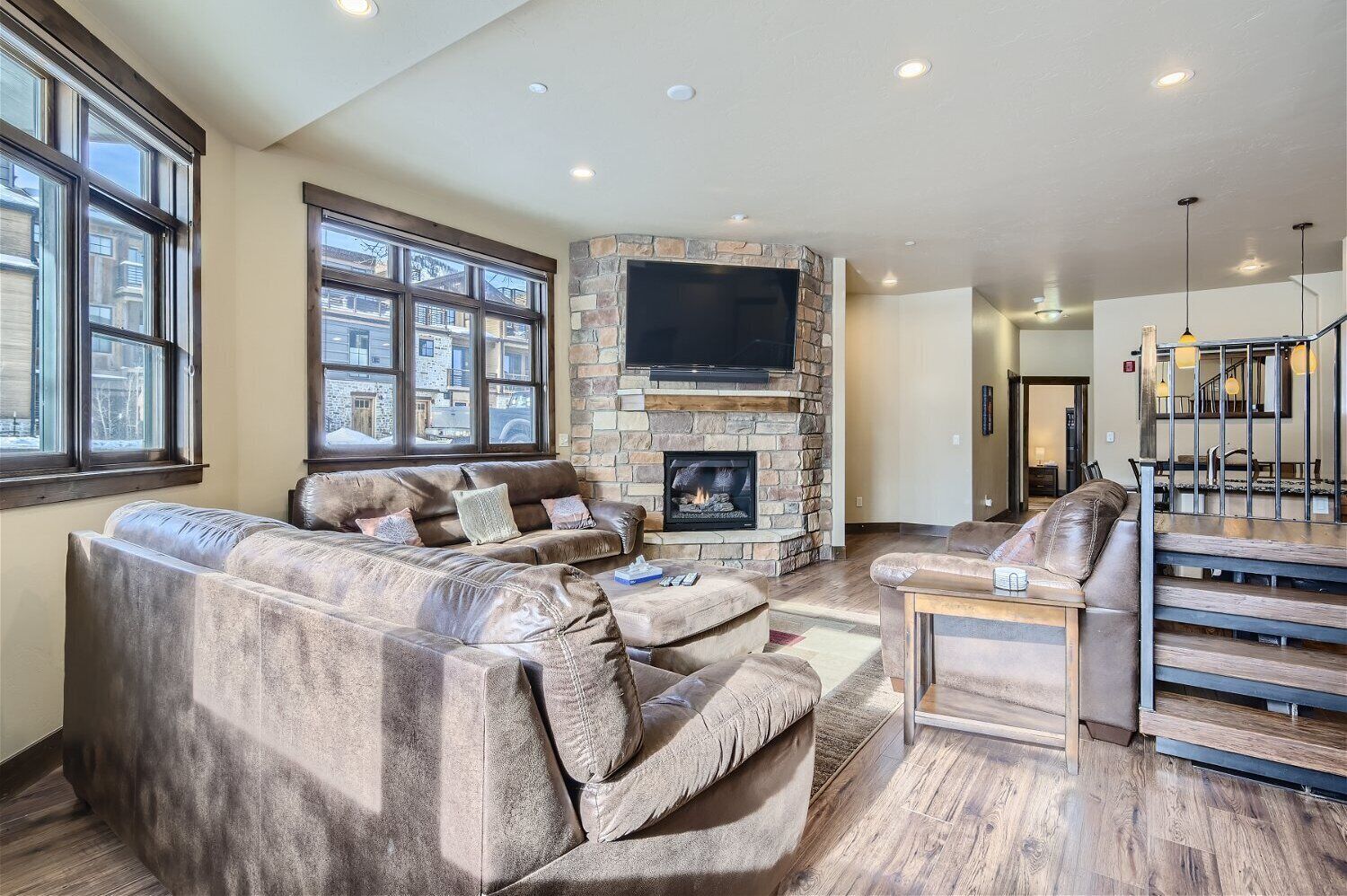 A spacious living room with a stone fireplace, leather sofas, and a large TV.