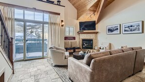 A cozy living room with a fireplace, comfortable seating, and a large window overlooking a snowy landscape. - Well Maintained 2 Bedroom Plus Loft Condo close to Lake Dillon!! (Frisco)