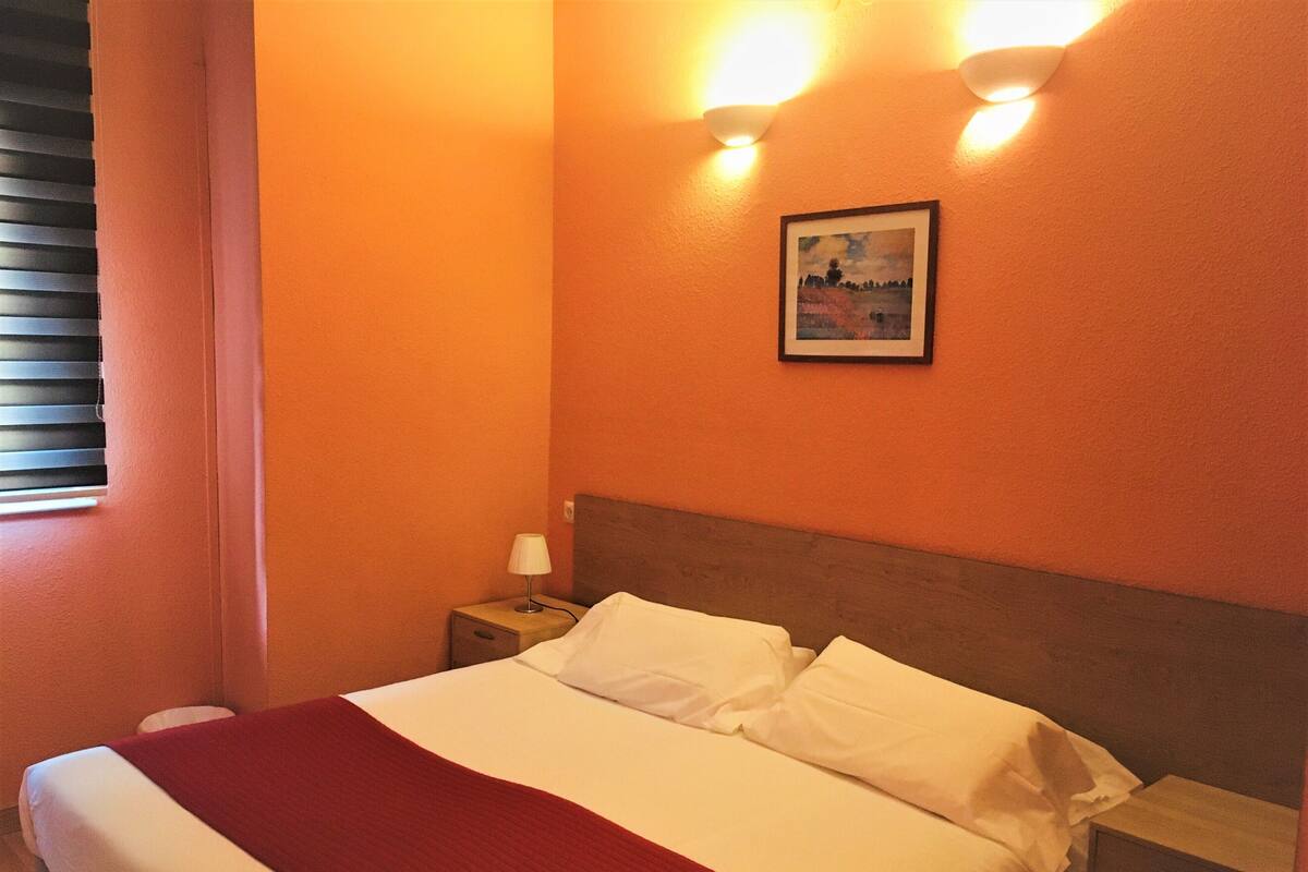 Une chambre d’hôtel avec un lit, une table de chevet, une lampe et un tableau au mur.