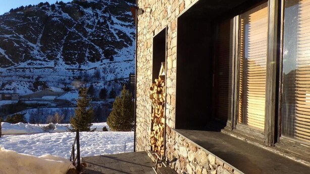A stone building with a window and a firewood stack outside. - Hotel Roc de St Miquel (Soldeu)