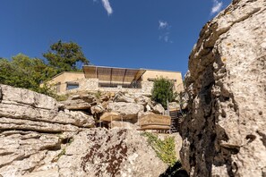 A building with a sloped roof, situated on rocky terrain with a clear sky above.
