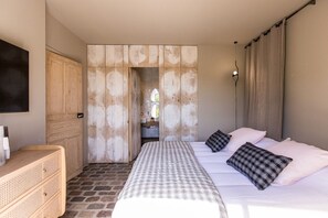 A bedroom with a bed, pillows, a wooden wardrobe, a bedside table, and a view through a door. - Gîte Laumaga I 4 pers. I Spa privé I Domaine le C4 (Casteljau)