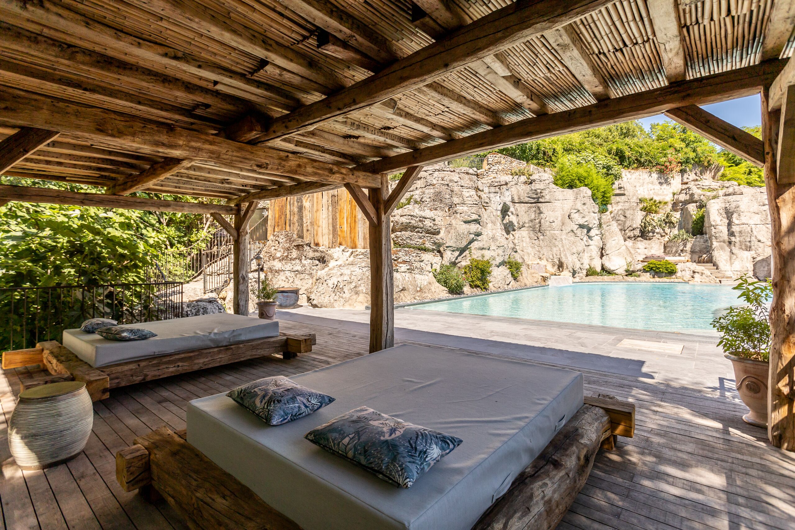 Une terrasse en bois avec deux lits et une piscine.