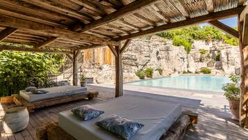 Une terrasse en bois avec deux lits et une piscine.