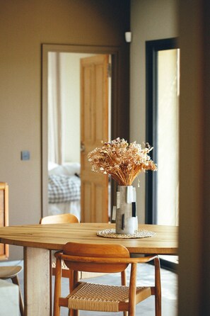 A dining table with a vase of dried flowers, a woven placemat, and a wooden chair. - Gîte Laumaga I 4 pers. I Spa privé I Domaine le C4 (Casteljau)